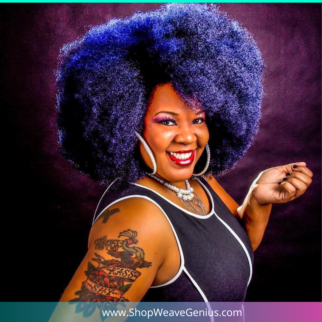 Woman with vibrant blue hair and tattoos posing against a dark background